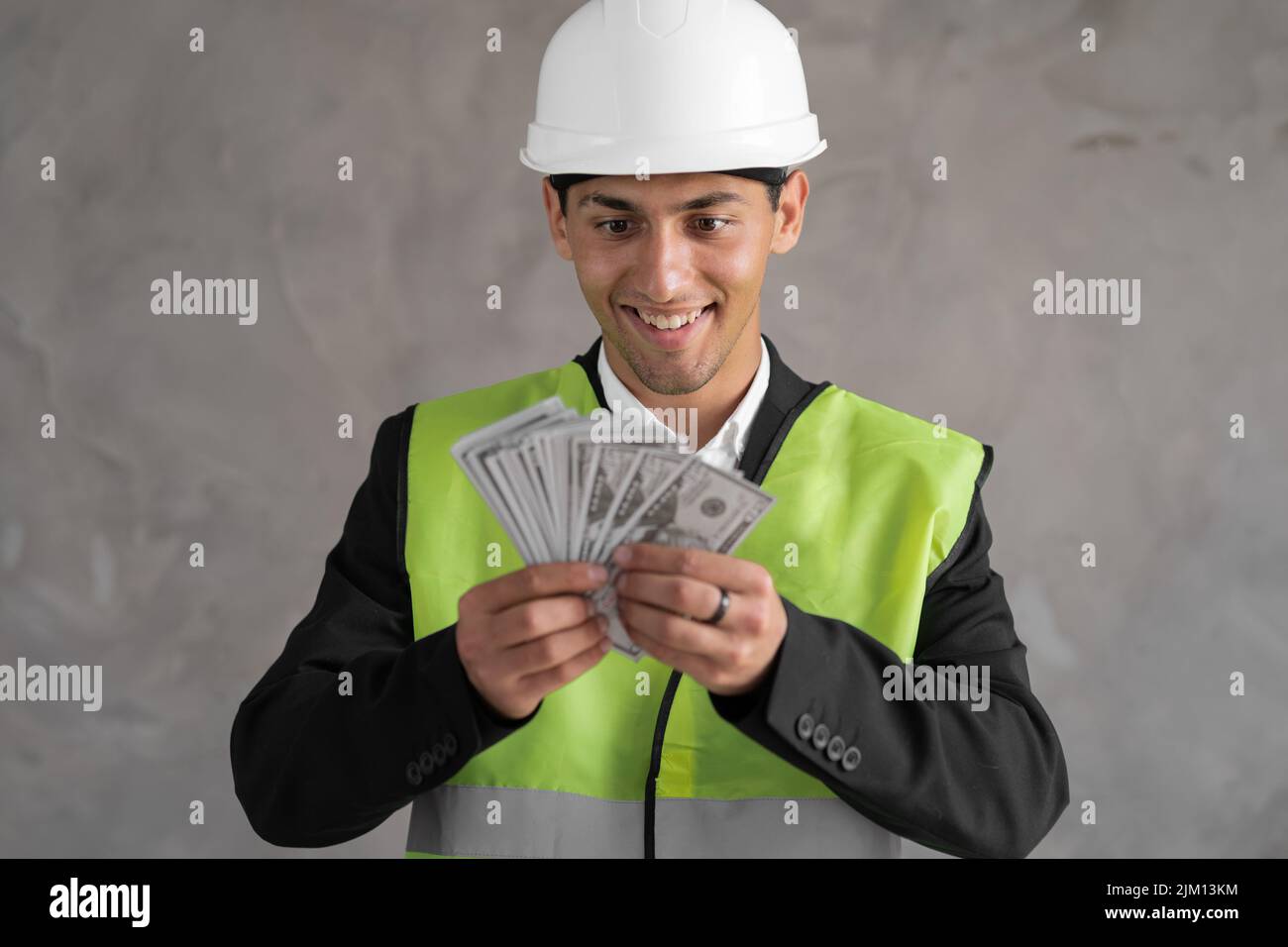 Young arabic builder man engineer wearing safety helmet holding dollars