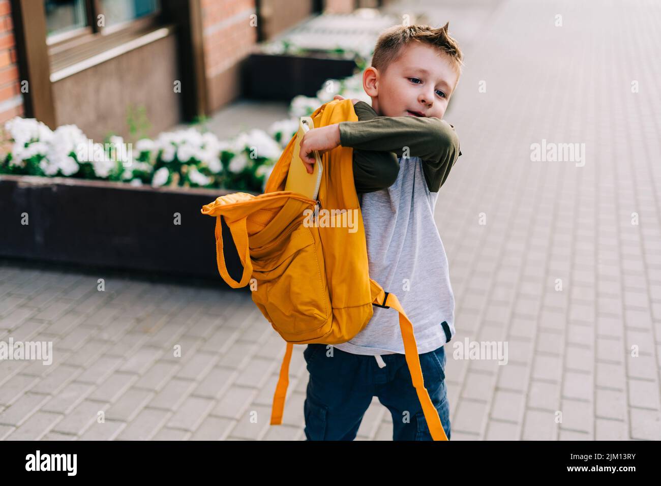 Back to school. Cute child packing backpack, holding notepad and training books going to school. Boy pupil with bag. Elementary school student going Stock Photo