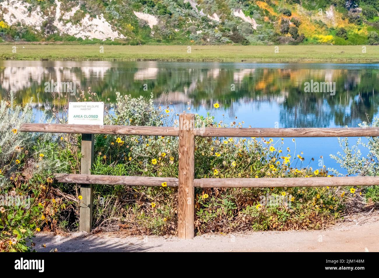 old wooden fence with flowers and reflections of the cliffs in the ...