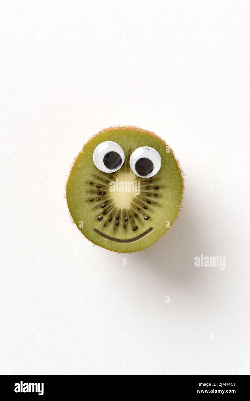 Fresh kiwi inside with face on white isolated background. Fruits and vegetables child healthy eating concept Stock Photo
