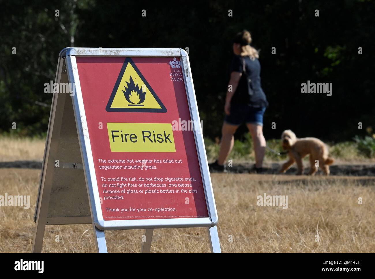 A person walks near a fire warning sign following a long period of hot weather and little rainfall, in Richmond Park, in London, Britain August 4, 2022. REUTERS/Toby Melville Stock Photo