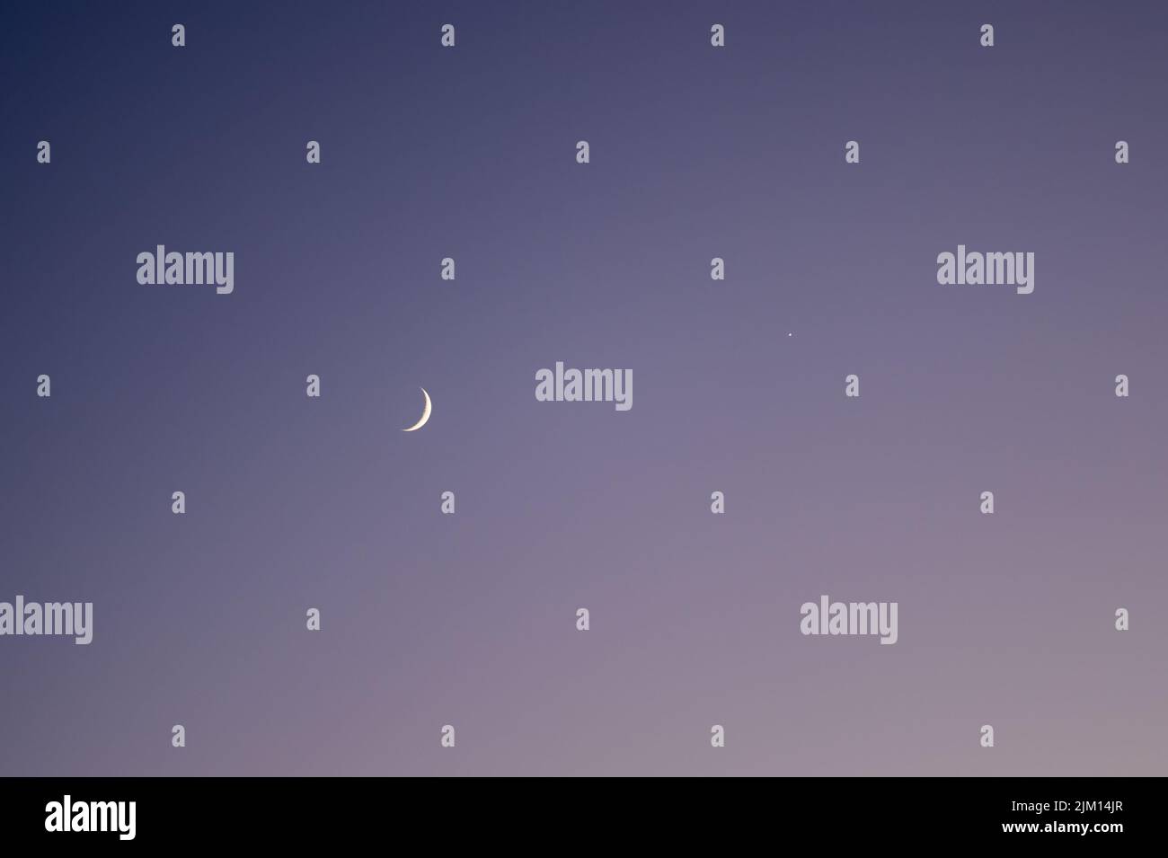 Crescent moon and venus in the dark evening sky. Stock Photo