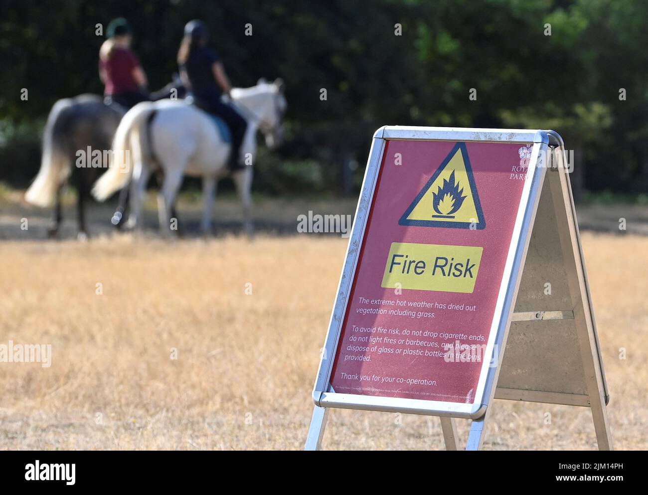 Horses are ridden near a fire warning sign following a long period of hot weather and little rainfall, Richmond Park in London, Britain, August 4, 2022. REUTERS/Toby Melville Stock Photo