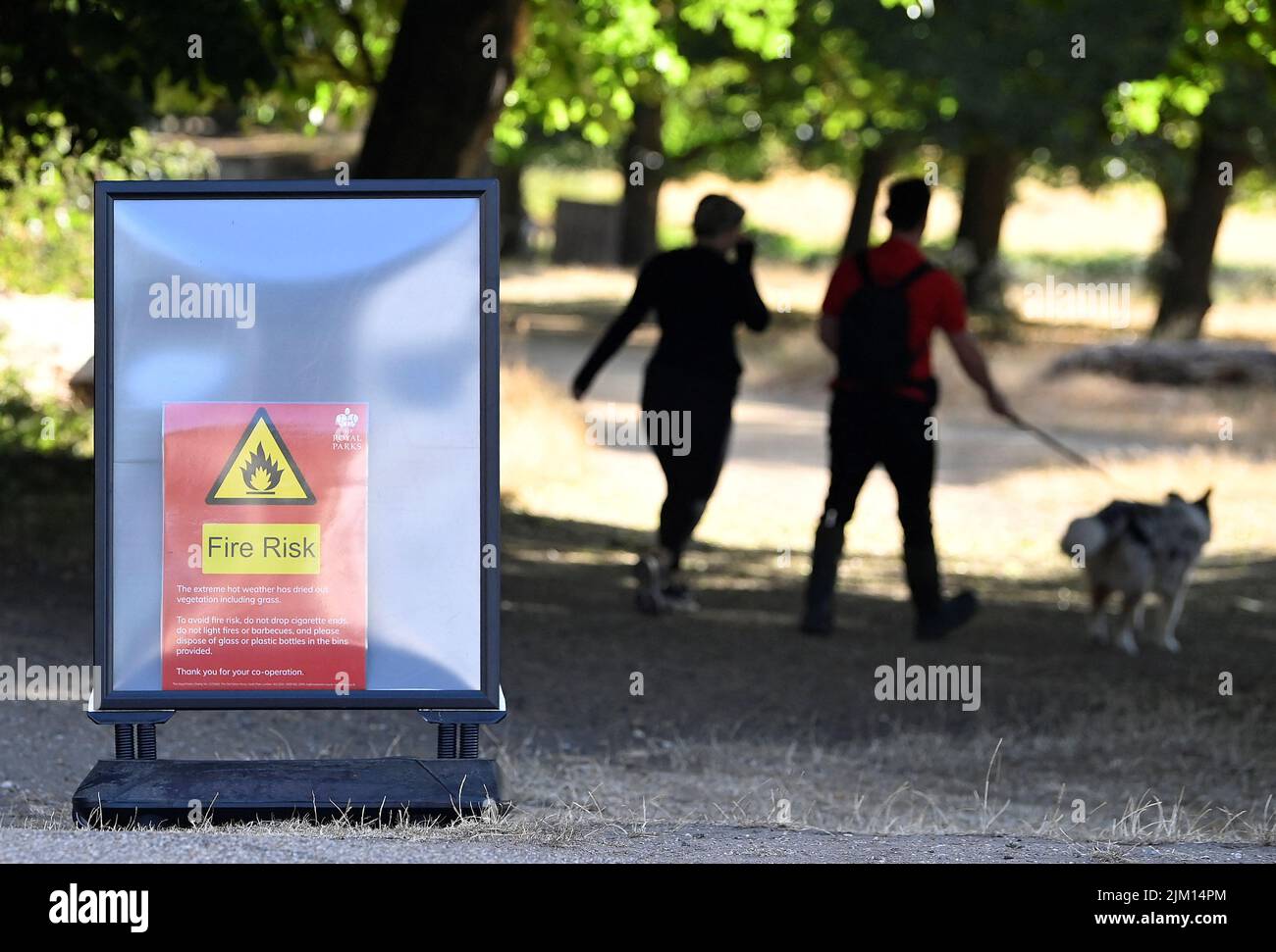 People walk near a fire warning sign following a long period of hot weather and little rainfall, in Richmond Park, in London, Britain August 4, 2022. REUTERS/Toby Melville Stock Photo