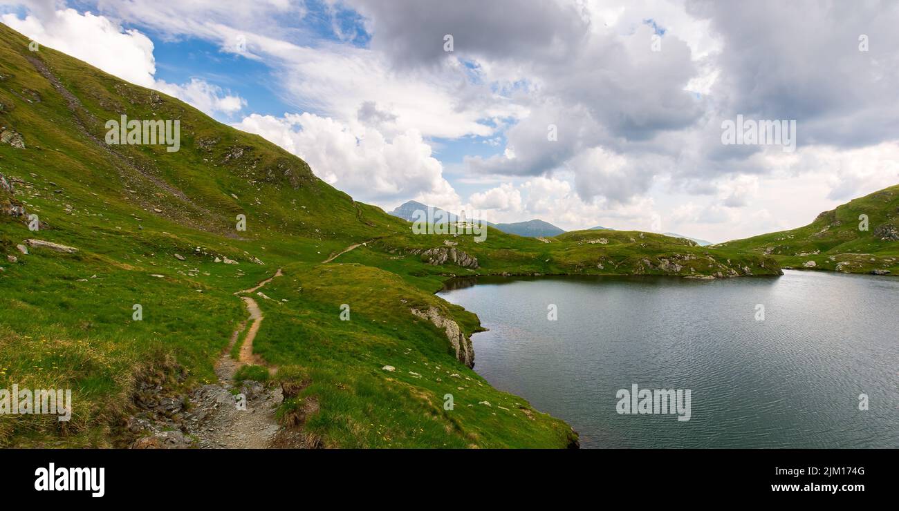 mountain landscape with lake in summer. beautiful travel destination of fagaras ridge, romania. scenic nature scene. outdoor adventure in green enviro Stock Photo