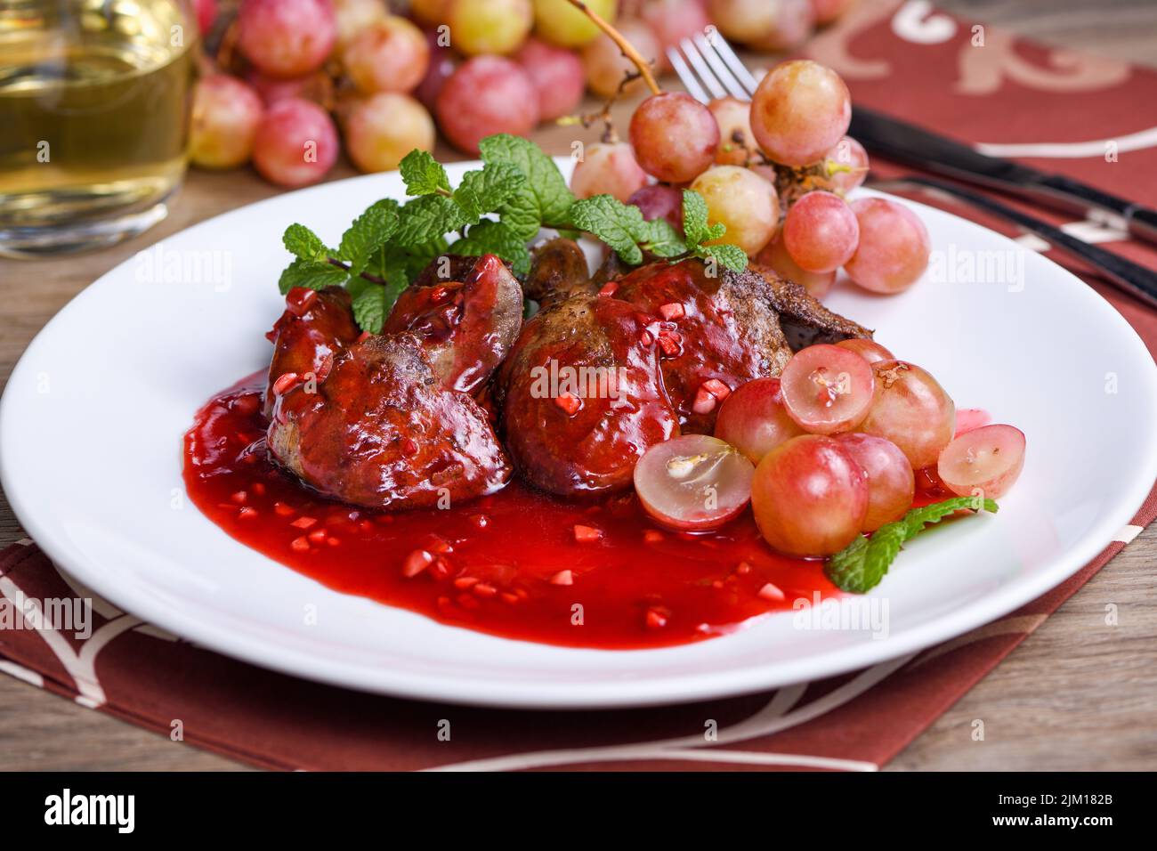 Warm salad with chicken liver and grapes on the plate. Warm salad from