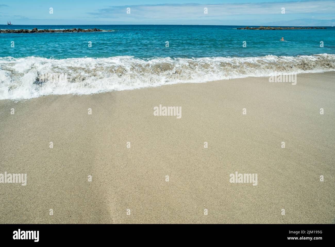 Ocean foam covering beautiful long sandy beach. Stock Photo