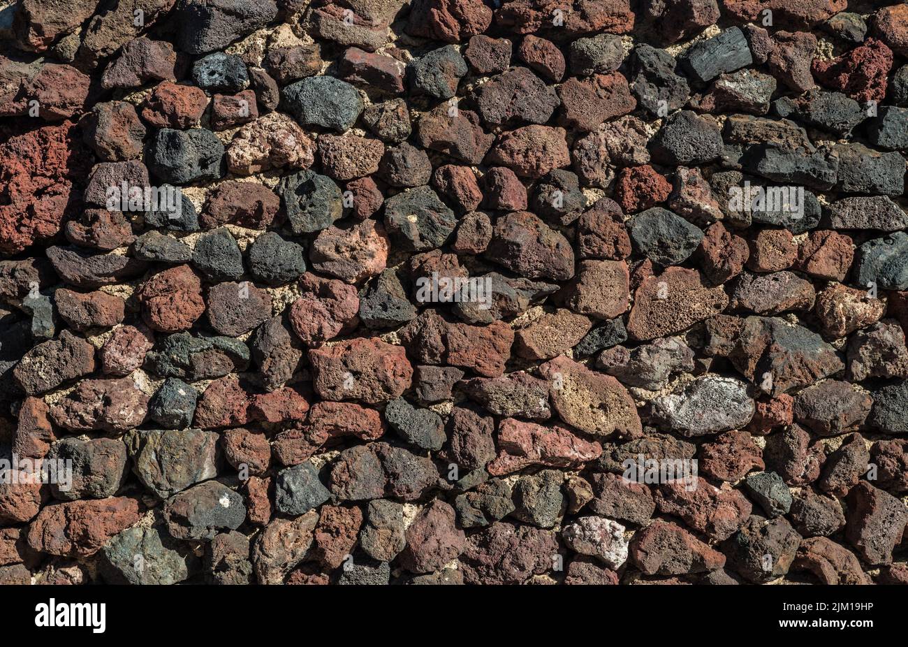 Wall built of lava remains or igneous rocks. Close-up. Stock Photo