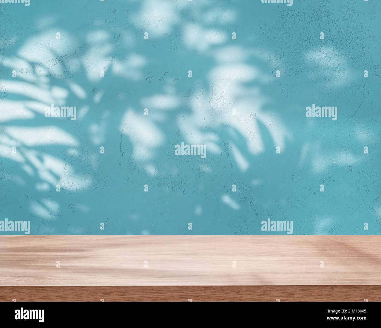 Empty board or table top and blue stucco pattern wall with leaf shadows. Place for your product display. Stock Photo