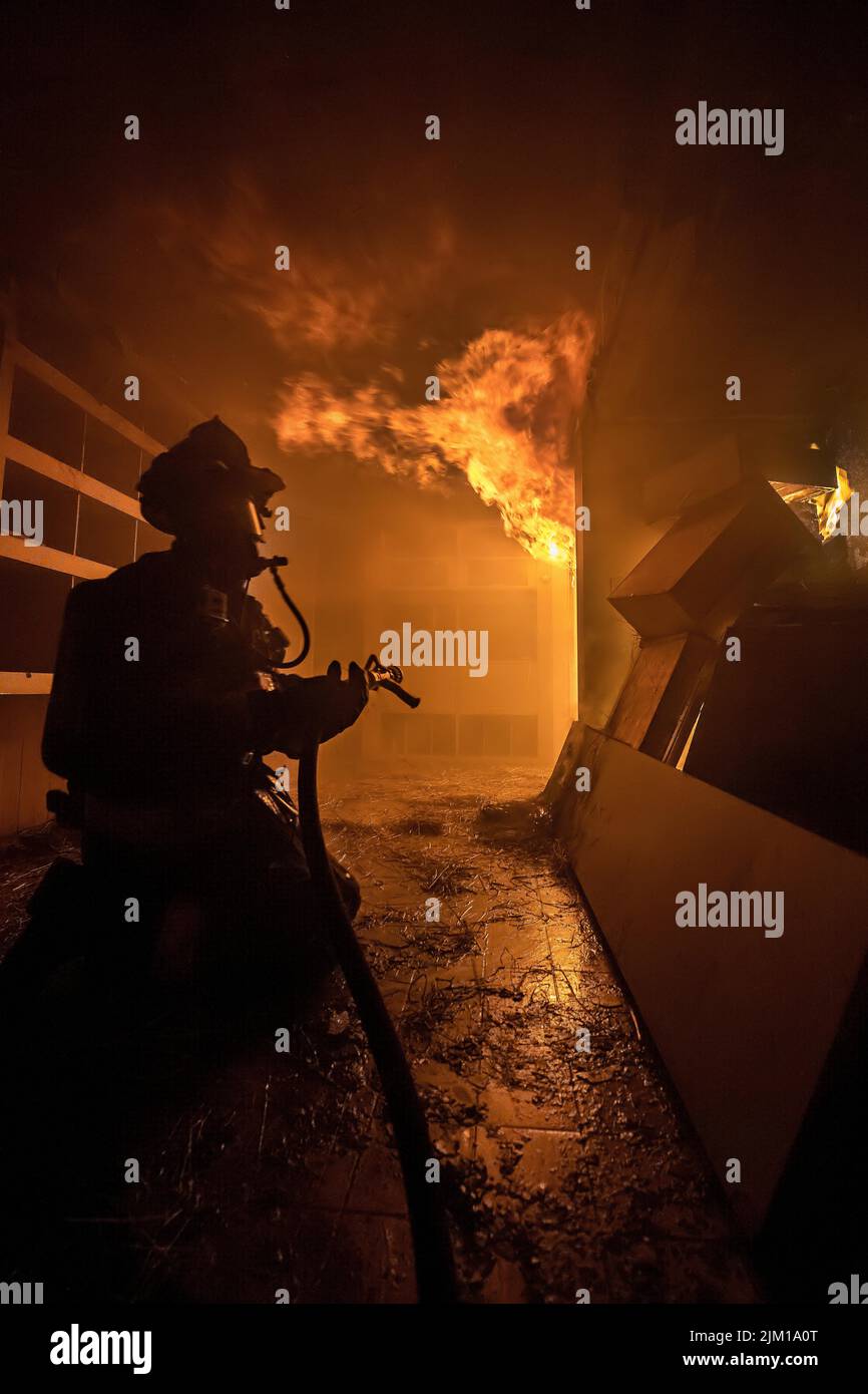 A firefighter waits for his hose to be charged with water before attacking the fire as members of the East Hampton Fire Department were joined by memb Stock Photo