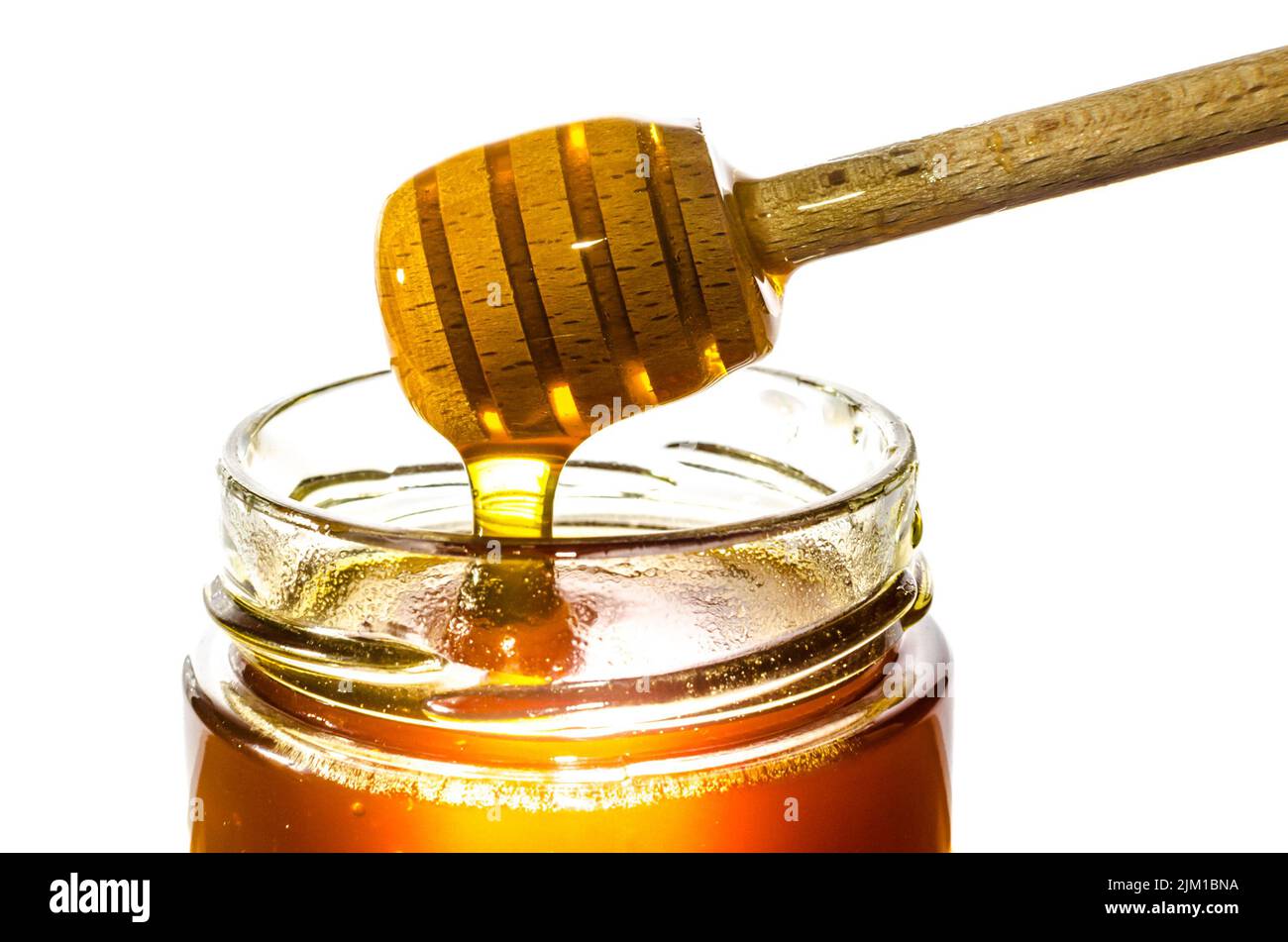 Getting honey from a jar with a honey spoon isolated on white background Stock Photo