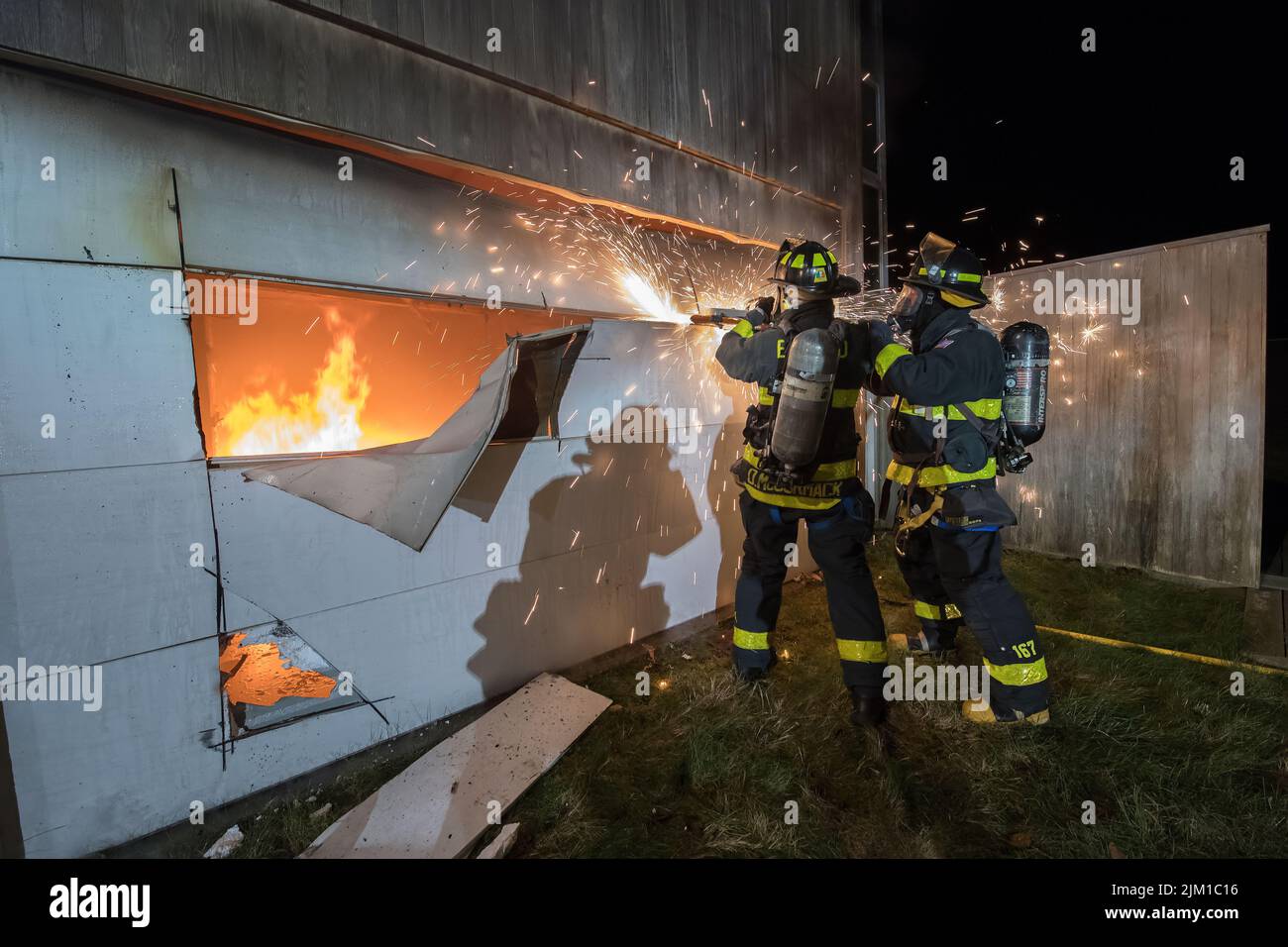 East Hampton firefightrers use a saw to cut open a garage door as members of the East Hampton Fire Department were joined by members for theSag Harbor Stock Photo