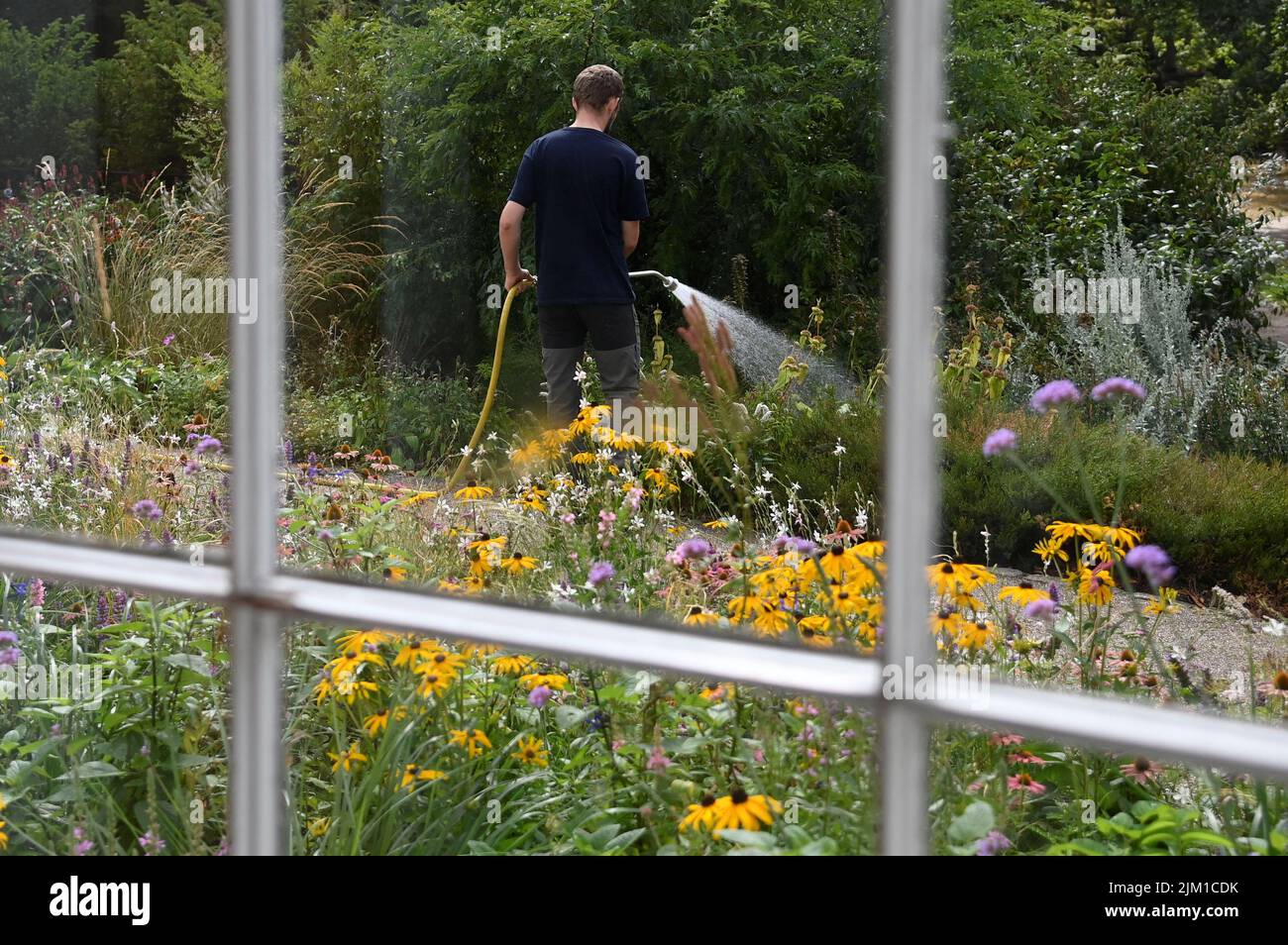 A worker waters plants in a public park, ahead of regional restrictions for private and residential water usage being implemented, in London, Britain, August 4, 2022. REUTERS/Toby Melville Stock Photo