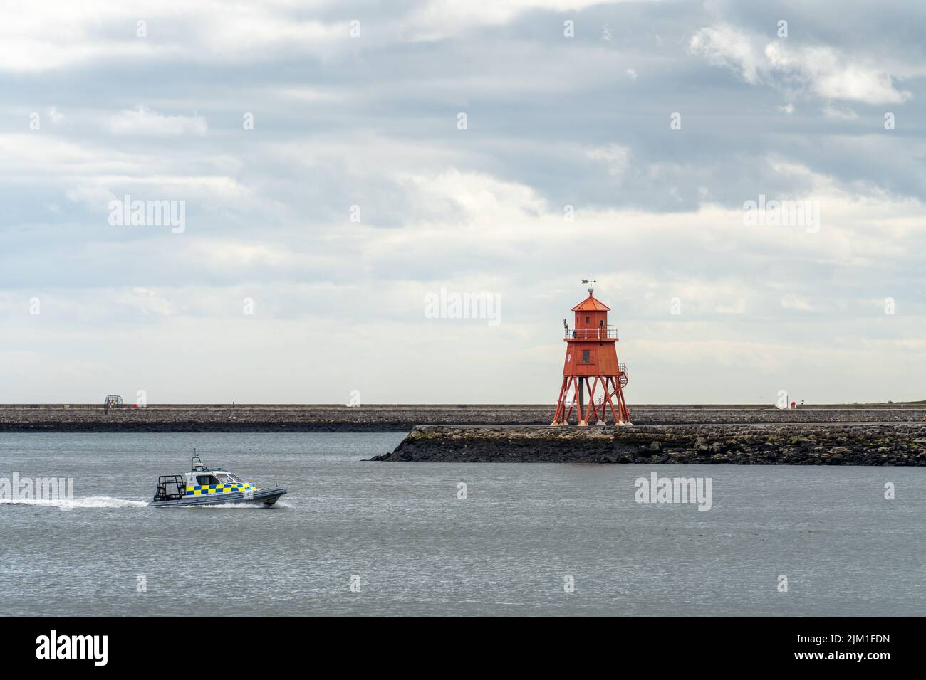 View of the Herd Groyne lighthouse, South Shields, UK, in the River Tyne, with a river police boat passing by. Stock Photo