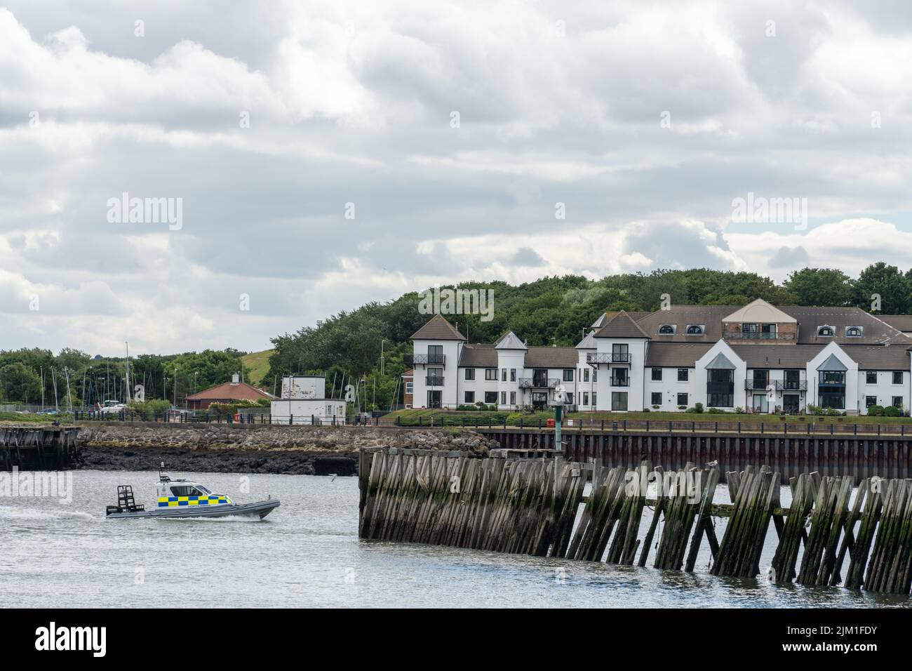 A riverscape view over the River Tyne to waterfront housing in South Shields, South Tyneside, UK, with the river police boat. Stock Photo
