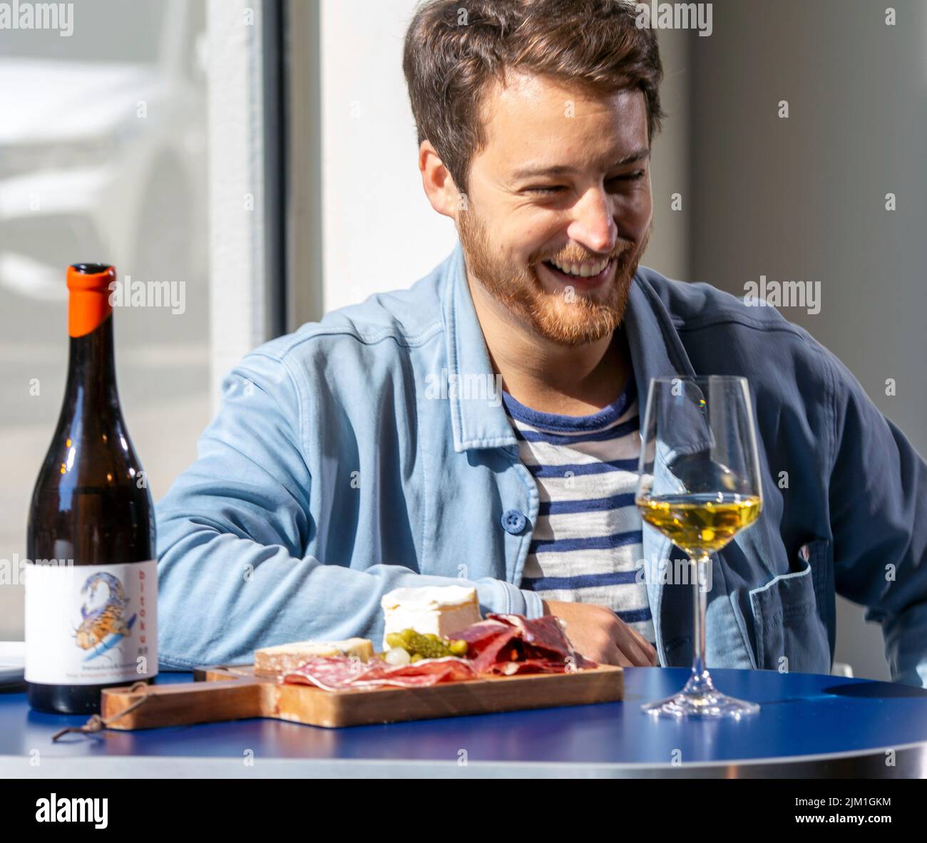 male with white wine glass ,charcuterie and cheese board . Stock Photo