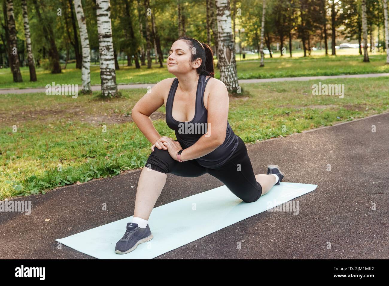 A charming brunette woman plus-size body positive practices sports in nature Stock Photo