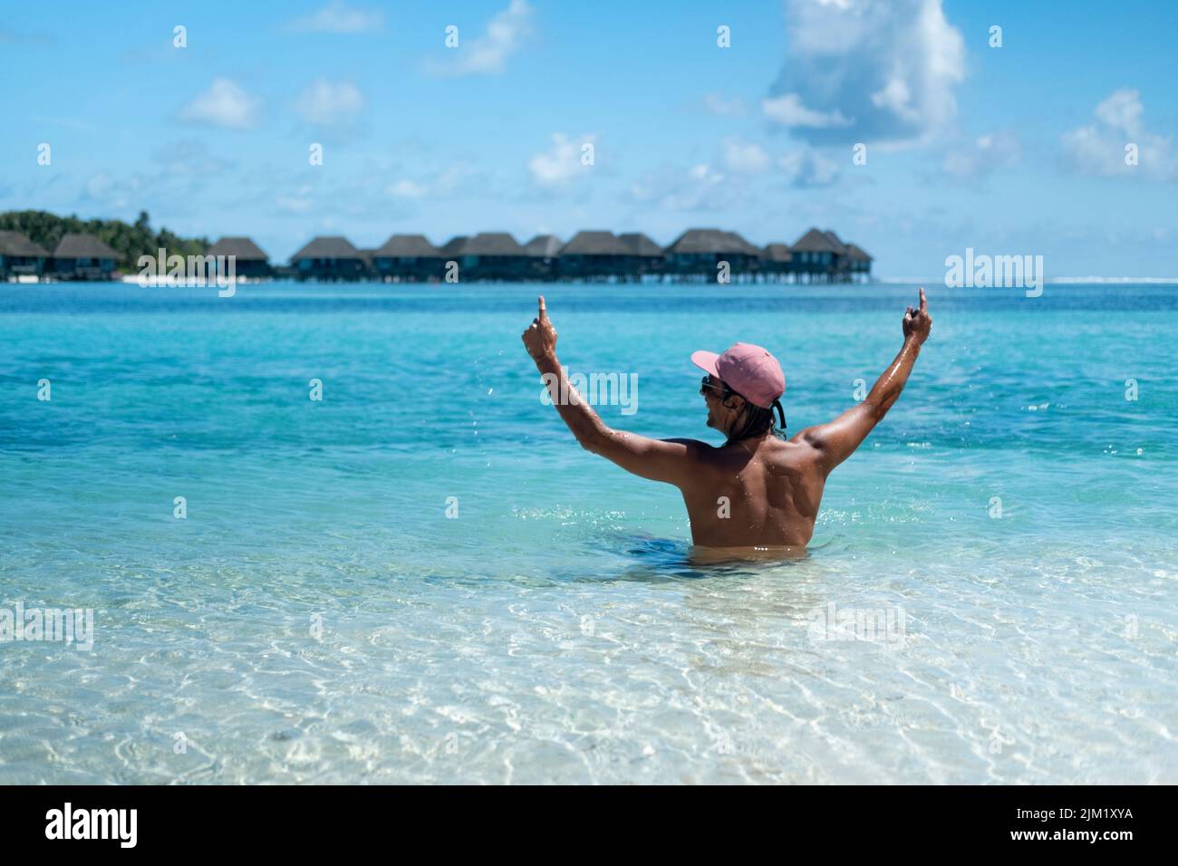 A man sits on the beach with amazing ocean views. Maldives Stock Photo