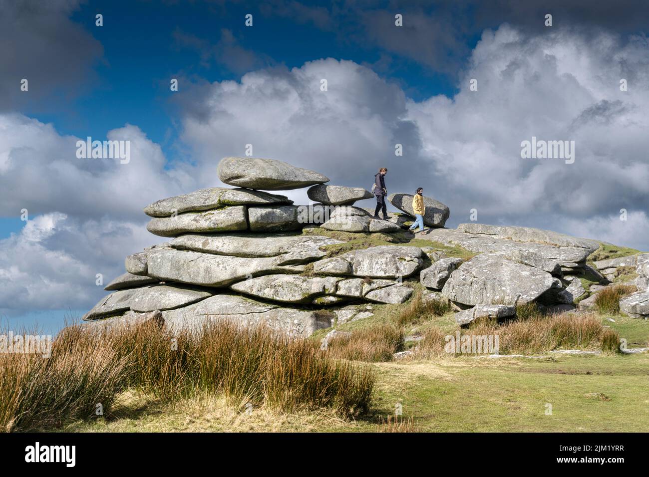 Walkers on the huge slabs of a granite rock stack formed by glacial action on the summit of Stowes Hill on Bodmin Moor in Cornwall. Stock Photo