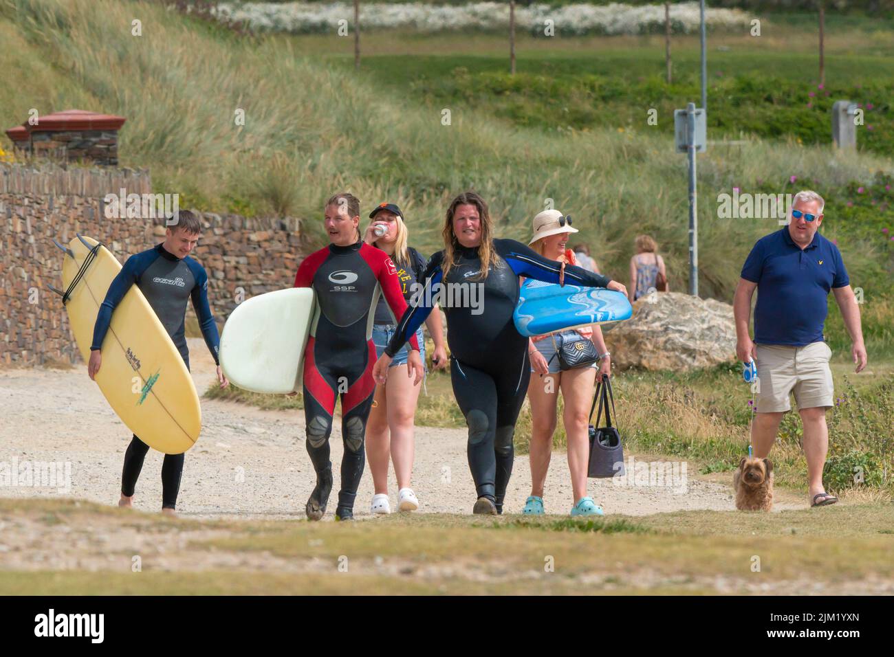 Holidaymakers and surfers walking on the coast path overlooking Fistral Bay in Newquay in Cornwall in the UK. Stock Photo