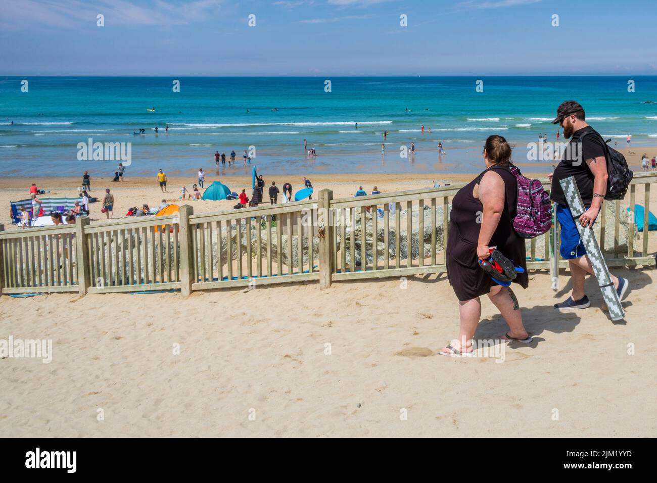Holidaymakers walking down to a busy Fistral Beach in Newquay in Cornwall in the UK. Stock Photo