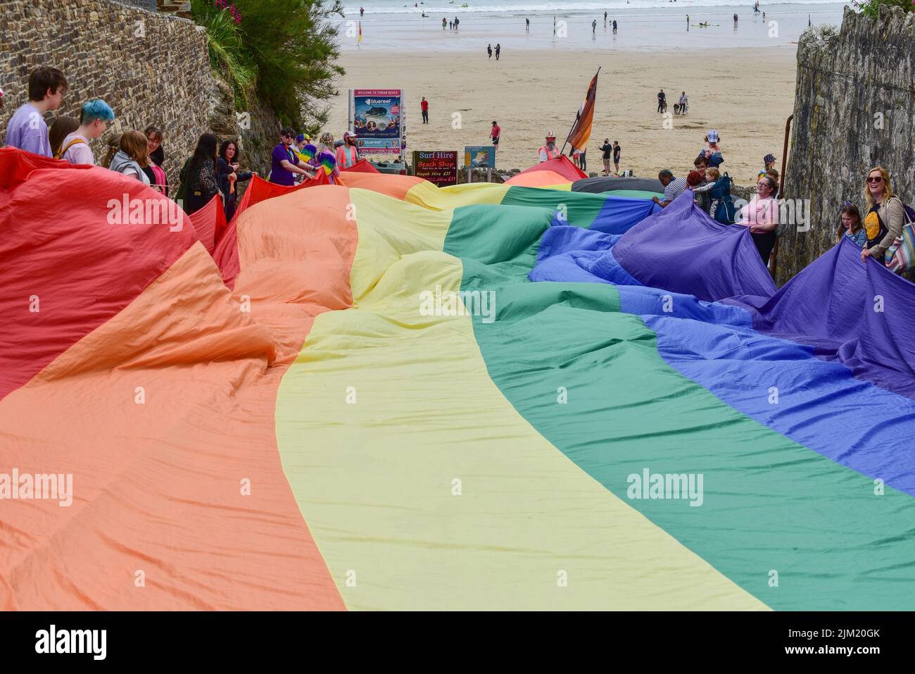 The huge vibrant colourful Cornwall Prides Pride flag banner held by participants in the parade at Towan Beach Newquay in the UK. Stock Photo