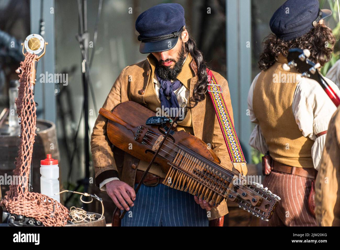 A musician from The Old Time Sailors tuning a nyckelharpa at the Newquay Orchard amphitheatre in Cornwall. Stock Photo