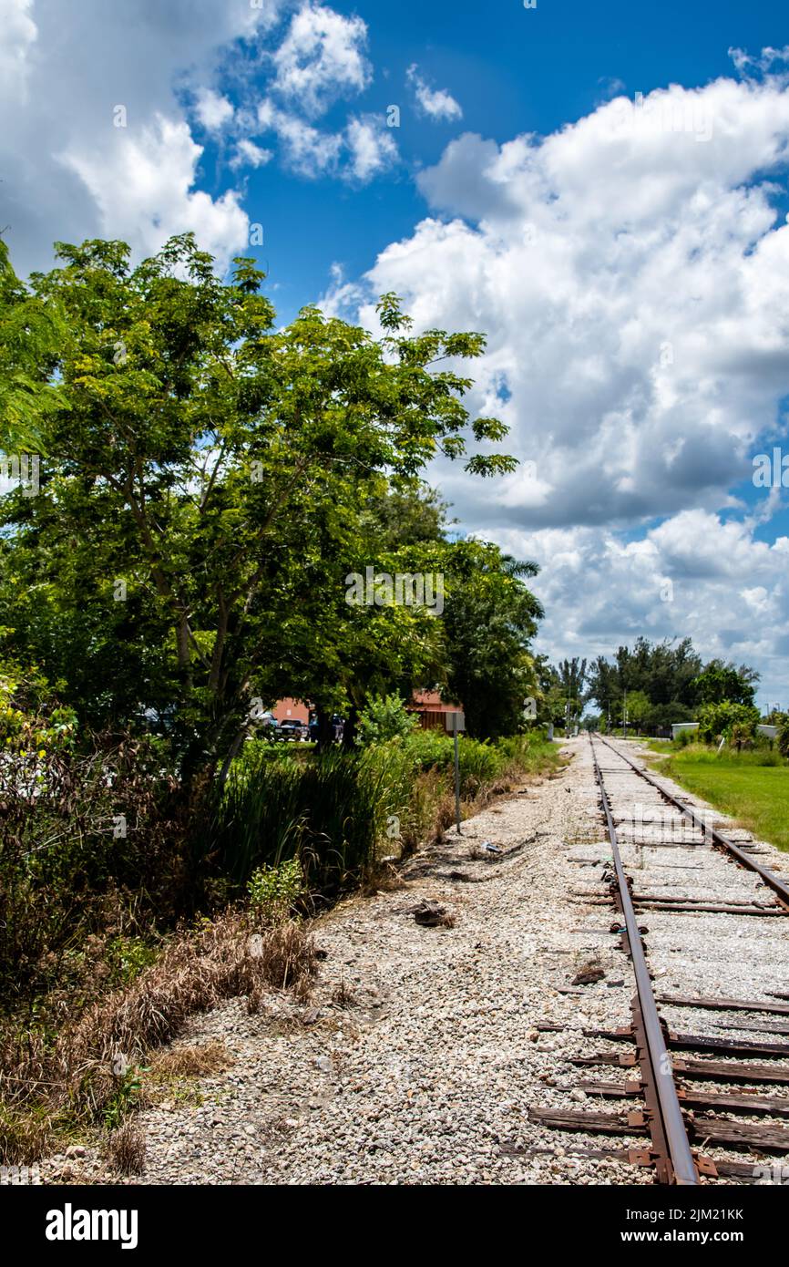 Railroad Tracks abandoned in desolate countryside, blue skies with clouds above, vertical orientation: Punta Gorda, Florida historical landmark Stock Photo