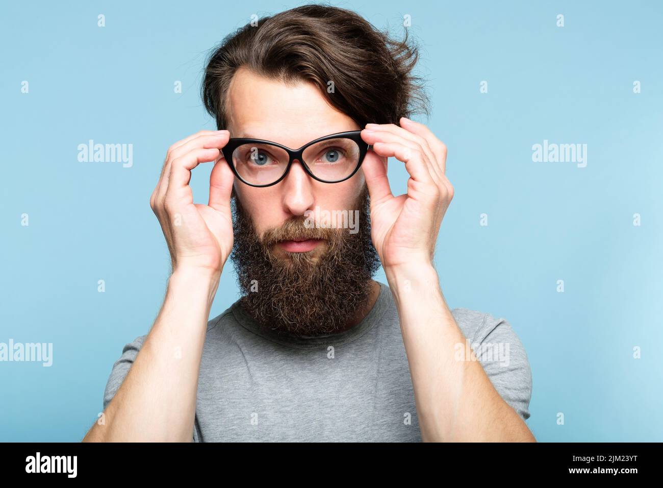 bearded hipster fixing cat eye glasses geeky man Stock Photo