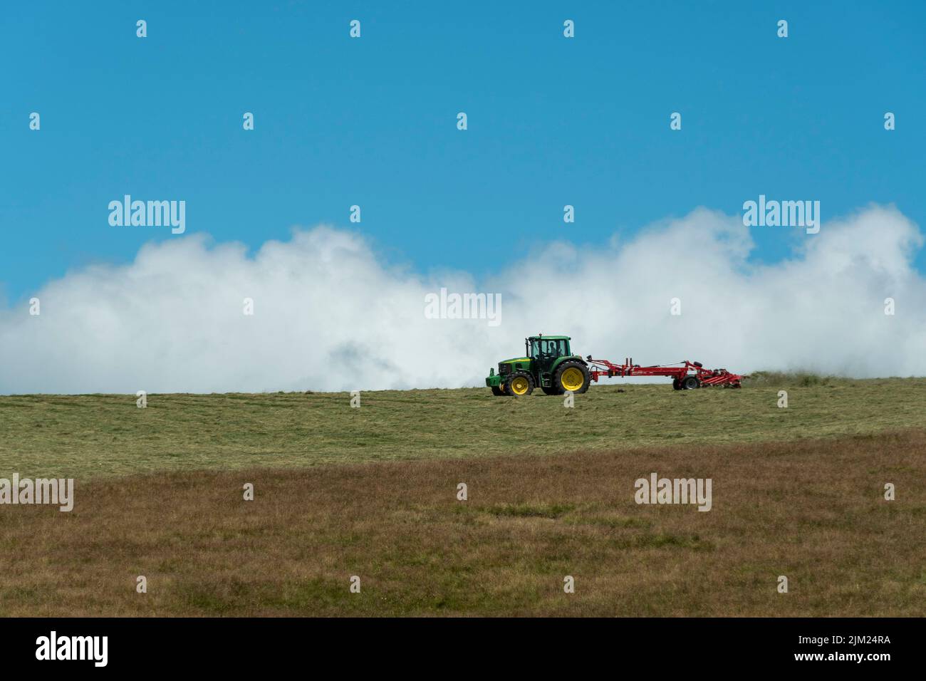 Tractor in a field in Sancy Massif, Auvergne Volcanoes Natural Park , Puy de Dome department, Auvergne Rhone Alpes, France Stock Photo