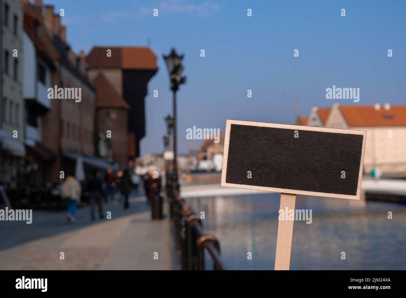 Empty mockup template Blackboard label against Gdansk beautiful old town over Motlawa river. The Zuraw Crane and colorful gothic facades of the old Stock Photo