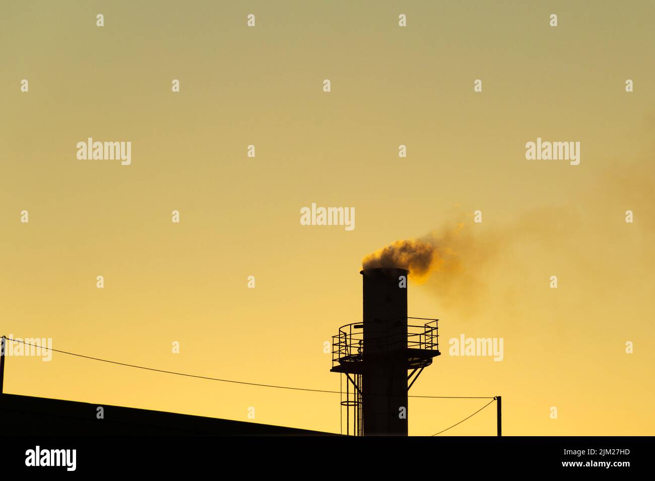 Goiania, Goiás, Brazil – August 04, 2022: Smoke coming out of a factory chimney. Air pollution from smoke coming out of the chimney with the golden da Stock Photo