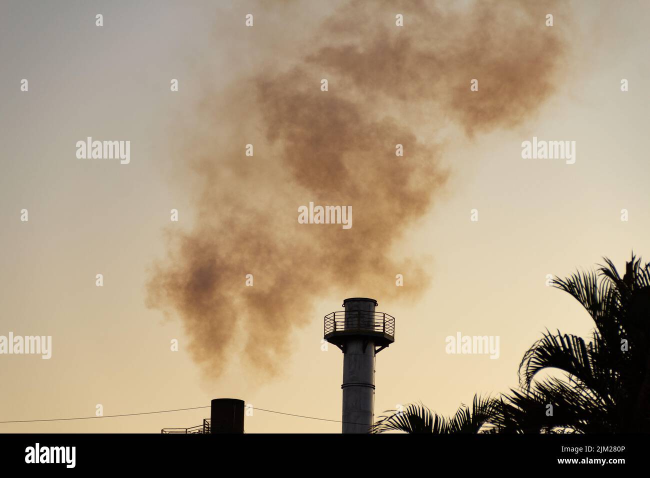 Goiania, Goiás, Brazil – August 04, 2022: Smoke rising from the chimneys of a factory. Factory smoke pollution with the sky in the background. Stock Photo