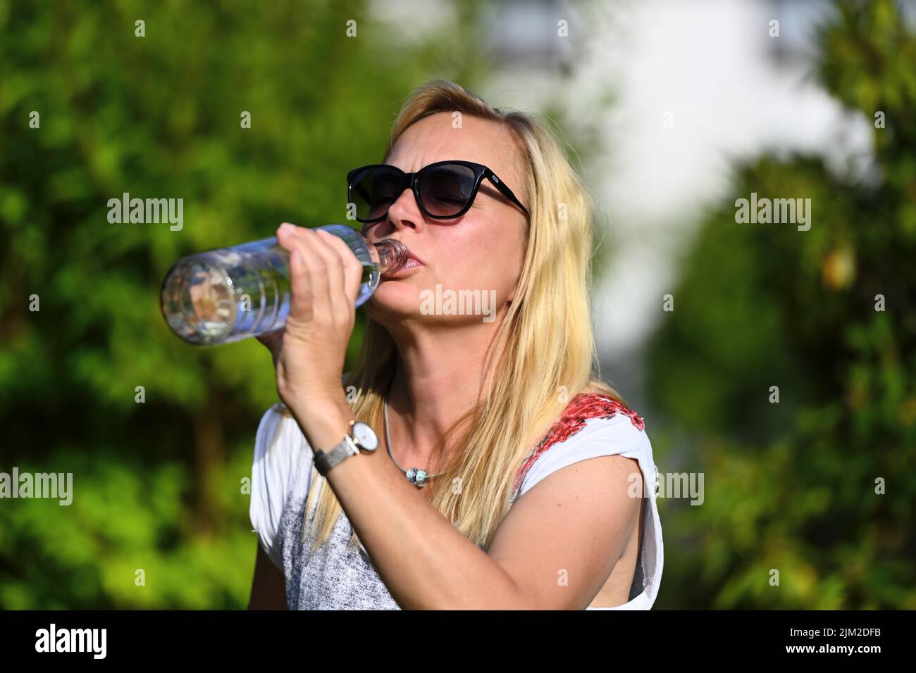 Woman Drinks Water In The Garden, Heat Wave Stock Photo