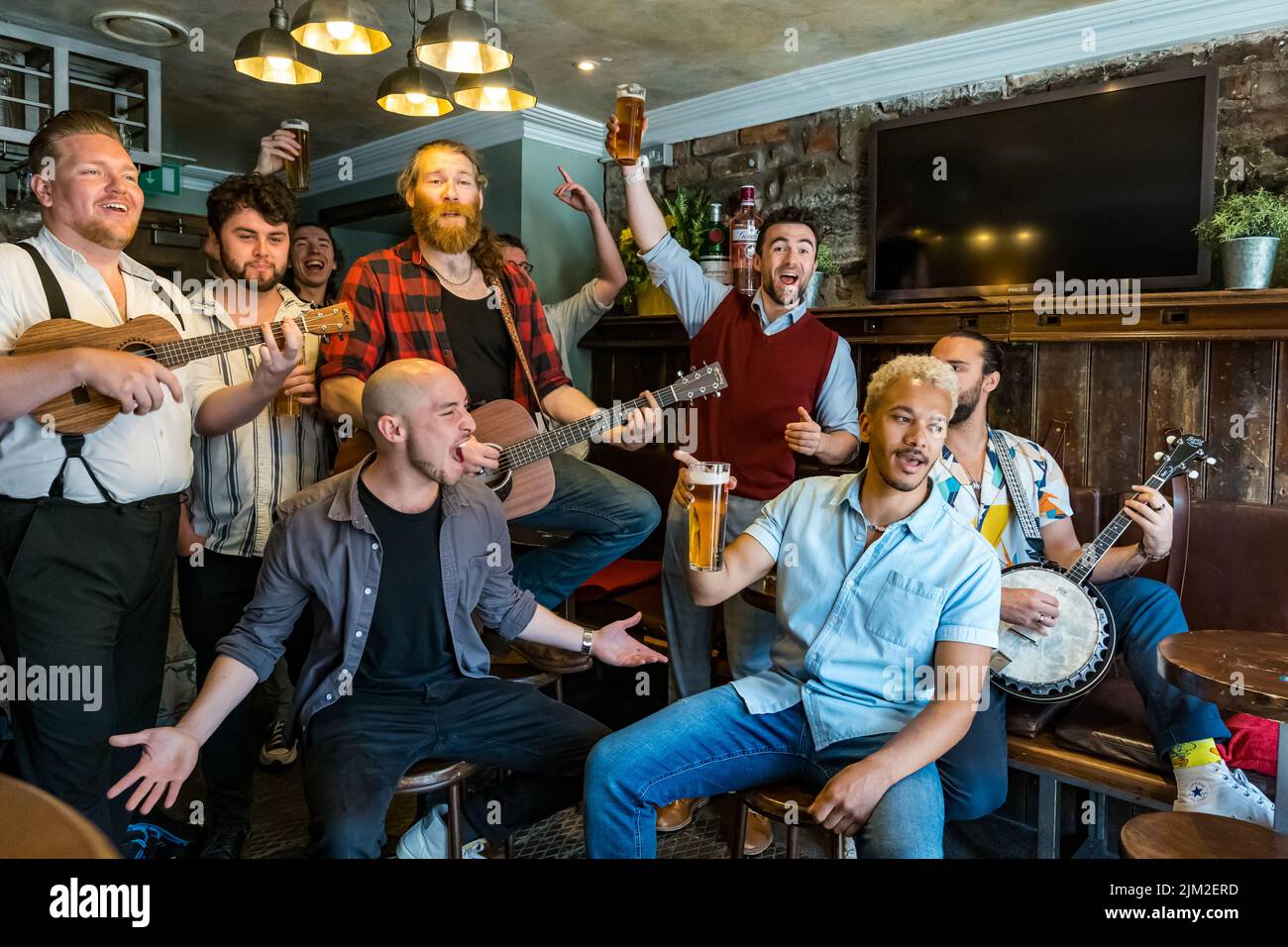 Edinburgh, Scotland, United Kingdom, 4th August 2022. Edinburgh Festival Fringe: The Chior of Man all male singong grup appearing at the Fringe this month enjoy a pint and a sing song at the Smallest Pub in Scotland in the Grassmarket before their appearance later today. Credit: Sally Anderson/Alamy Live News Stock Photo