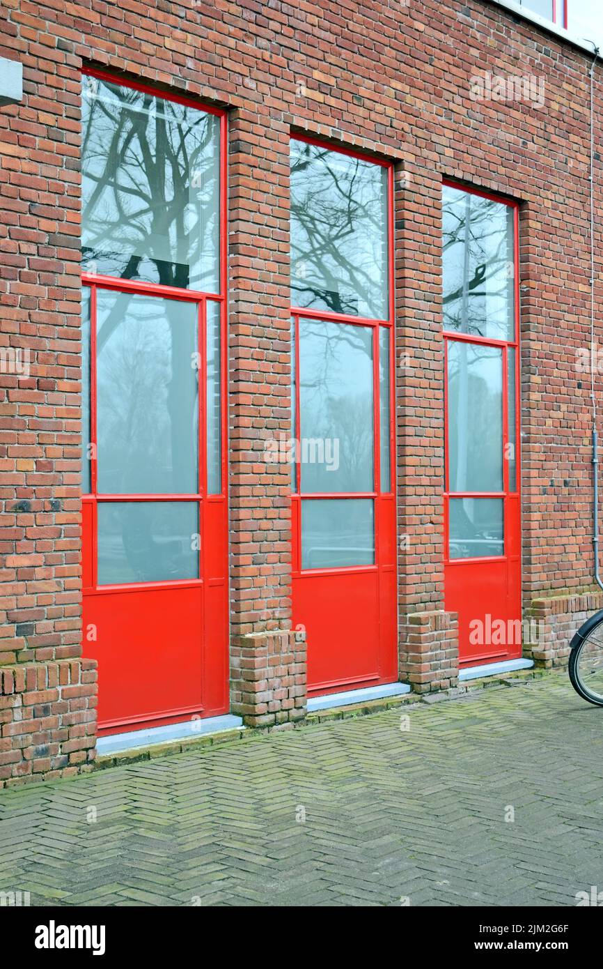few red doors with big glass windows on the brick wall, building industry diversity Stock Photo