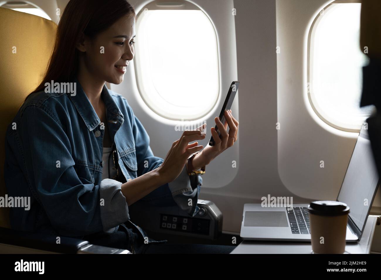 Beautiful asian travel woman using mobile phone in airplane. Stock Photo