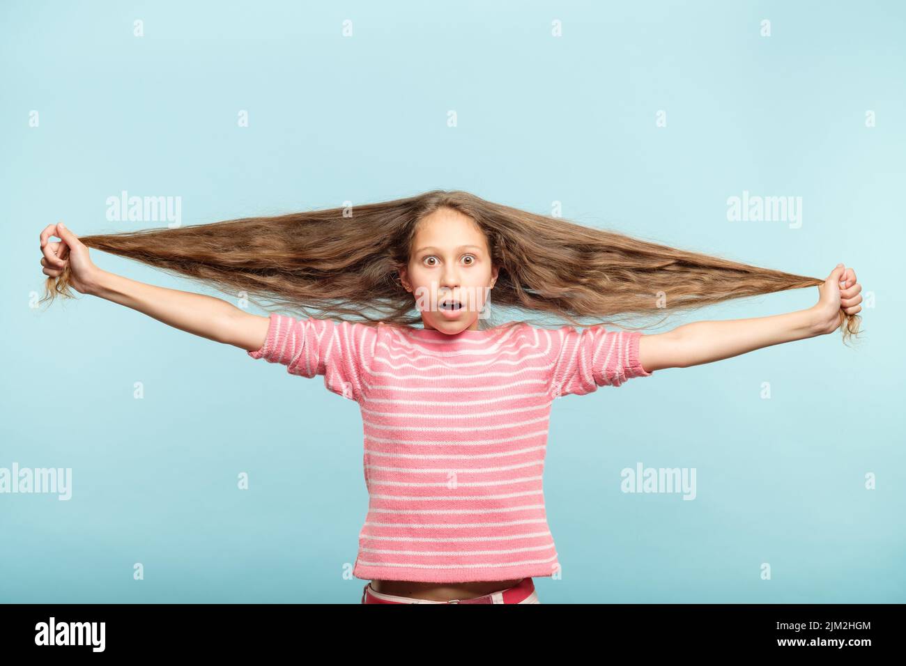 haircare styling shocked girl hold long wavy hair Stock Photo