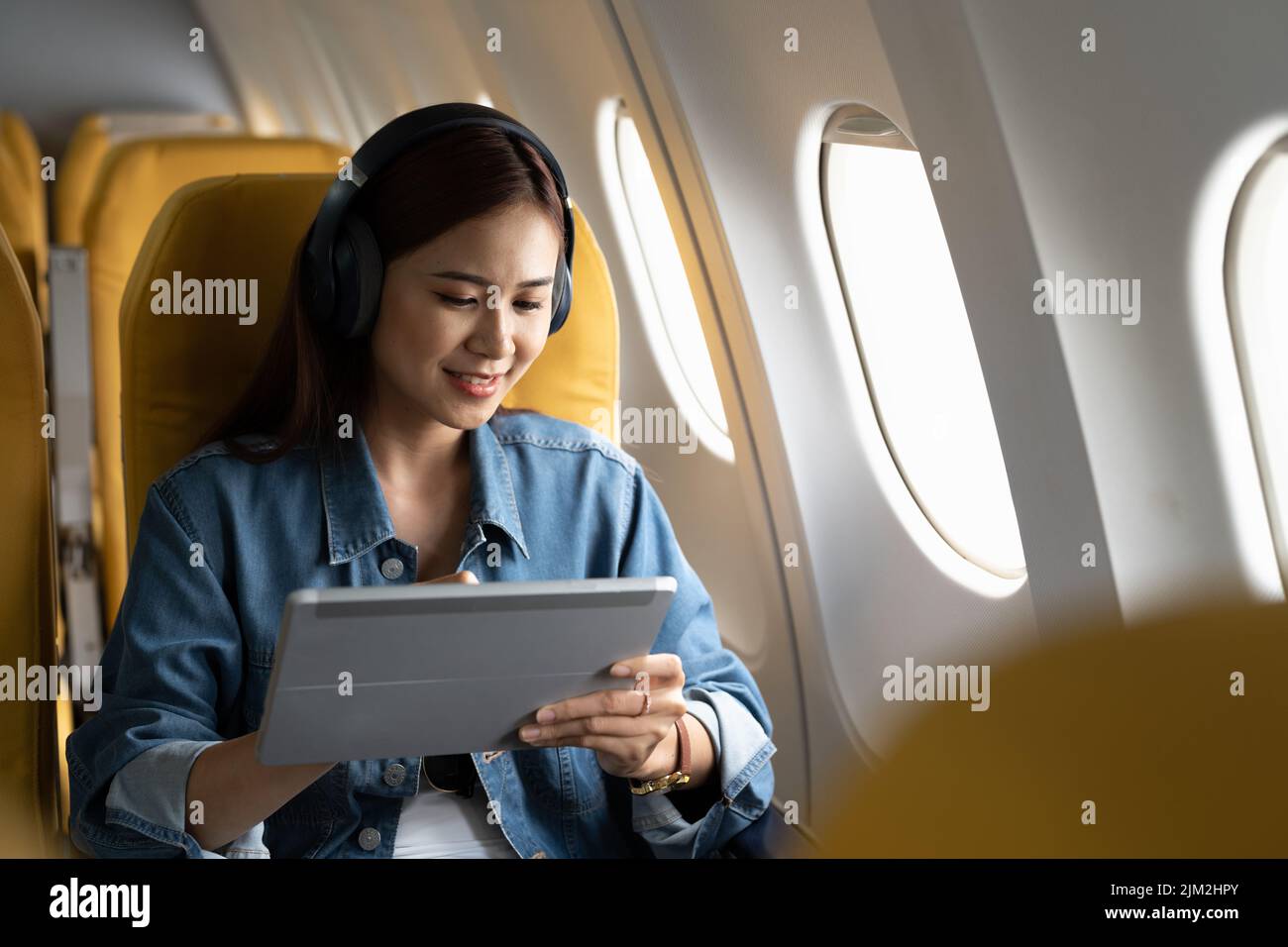 Beautiful asian travel woman watching movie on digital tablet in airplane Stock Photo
