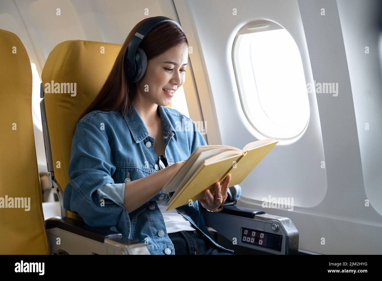 Beautiful asian travel woman reading a book in airplane Stock Photo
