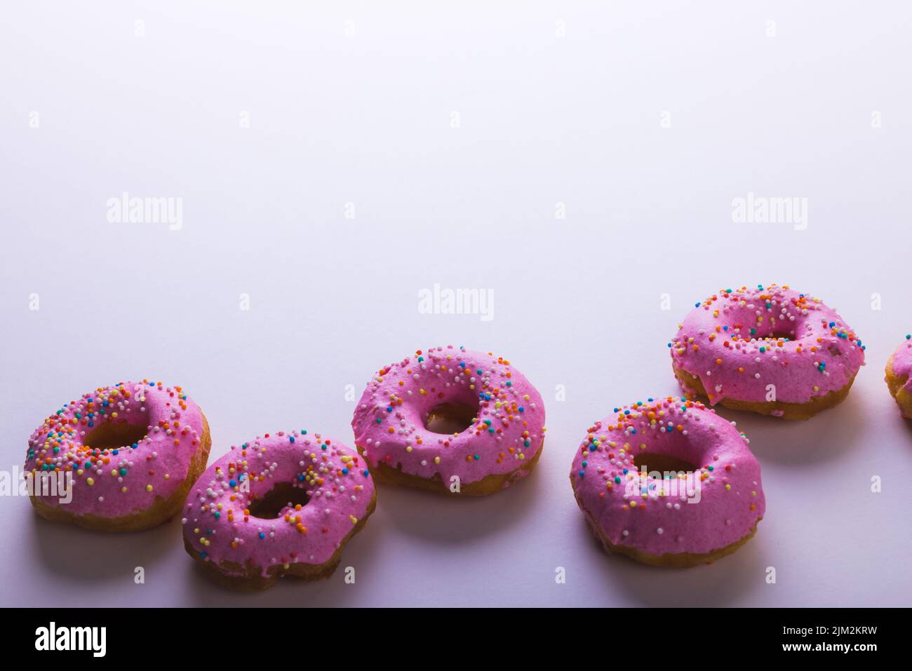 High angle view of fresh pink donuts with copy space against white background. unaltered, unhealthy eating and sweet food concept. Stock Photo