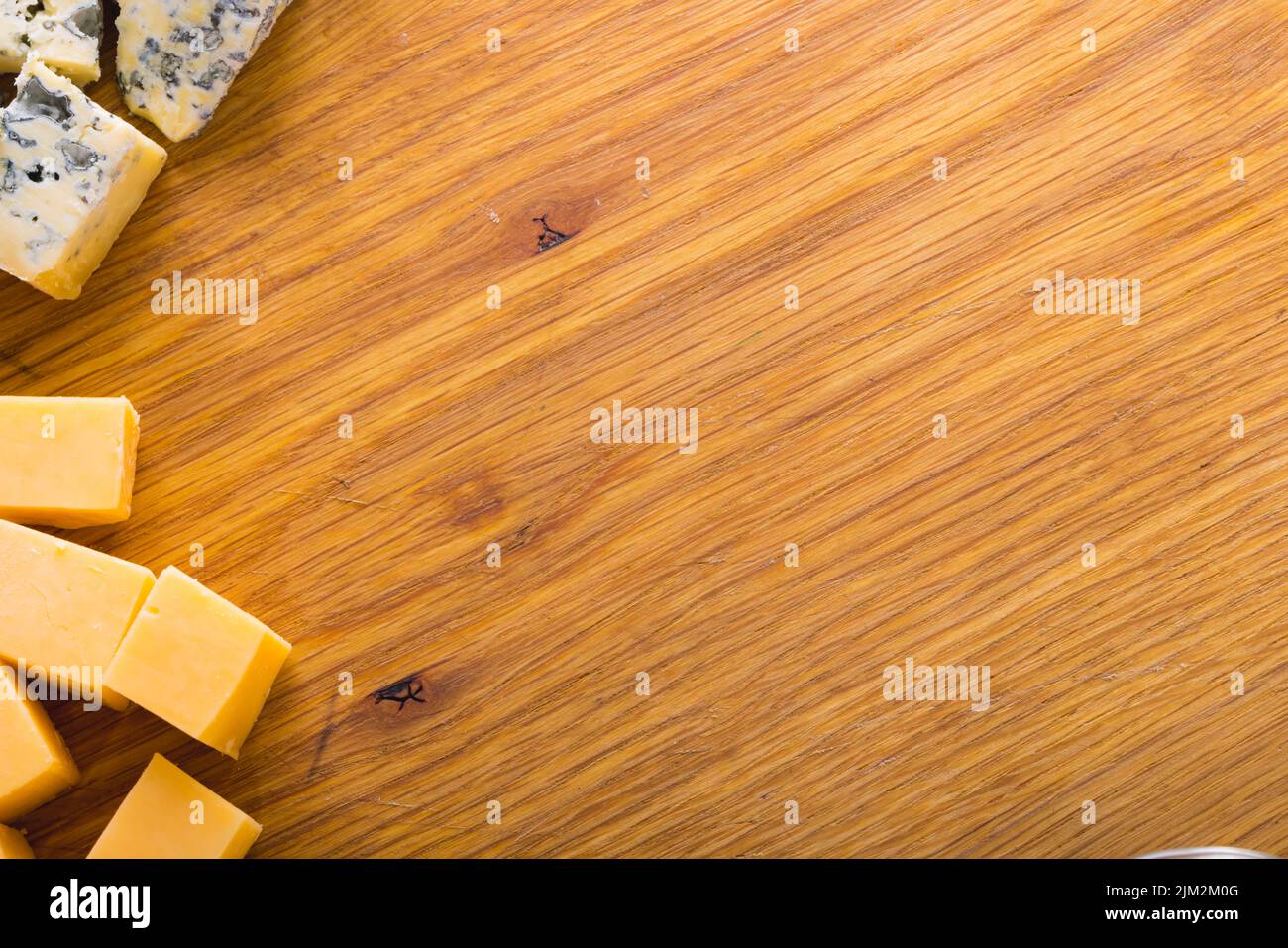 Overhead view of various cheese slices on wooden board, copy space Stock Photo