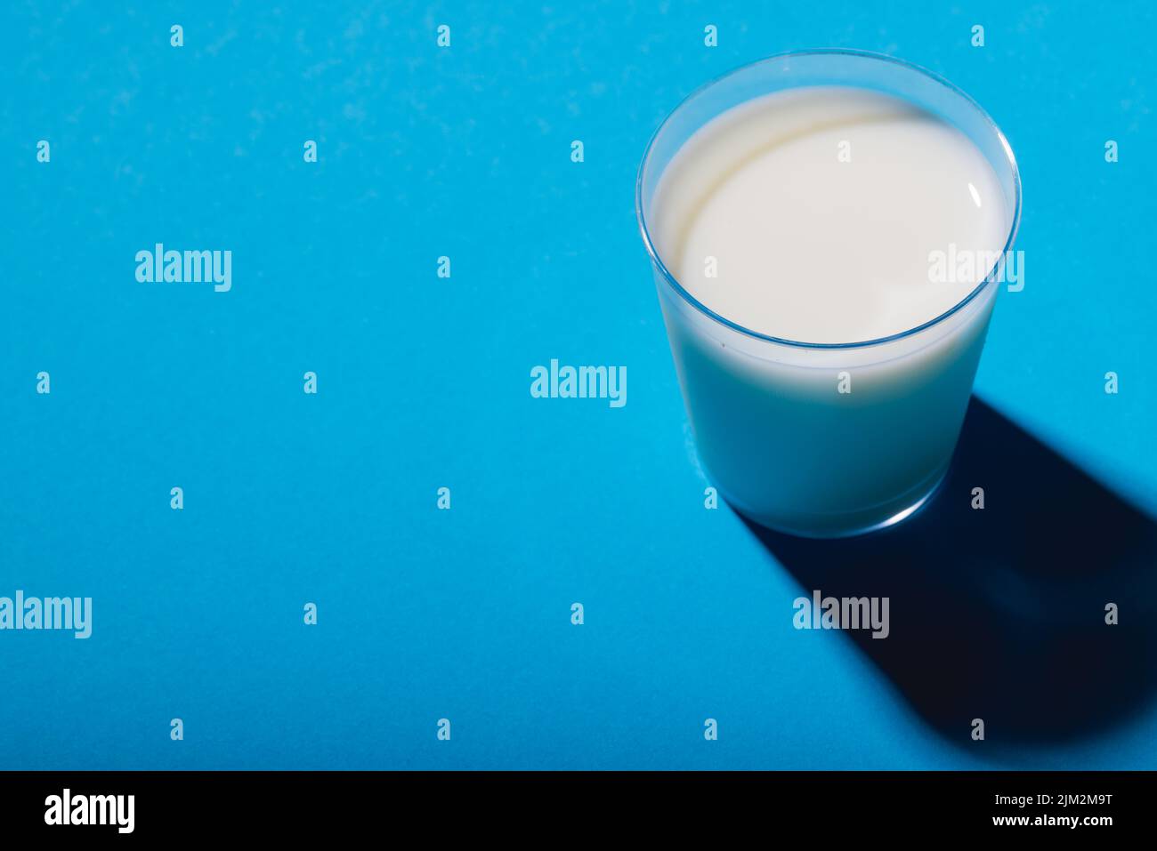 High angle view of glass of milk on blue background with copy space. unaltered, food, drink, studio shot and healthy food concept. Stock Photo