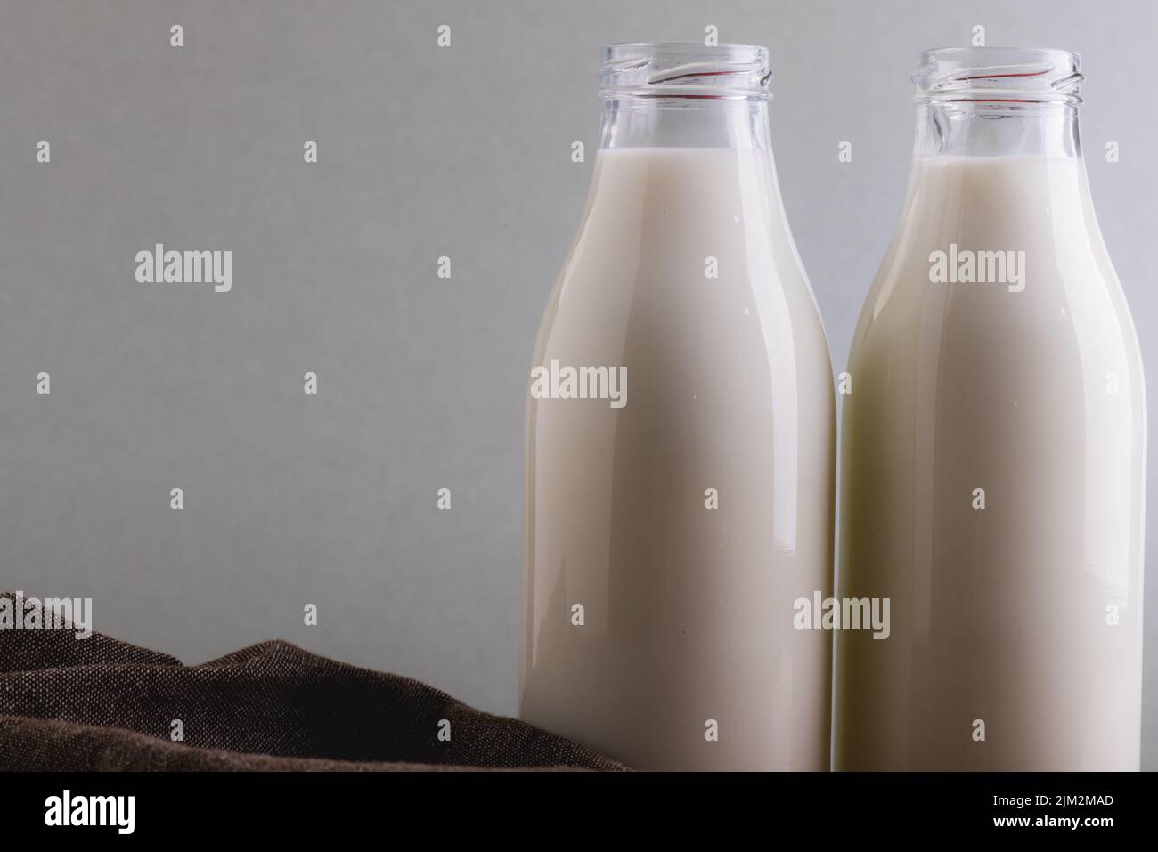 Close-up of milk in glass bottles against gray background with copy space. unaltered, food, drink, studio shot and healthy food concept. Stock Photo