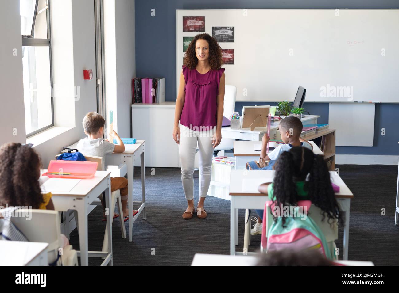 Smiling caucasian young female teacher looking at multiracial elementary school children in class. unaltered, education, teaching, childhood, occupati Stock Photo