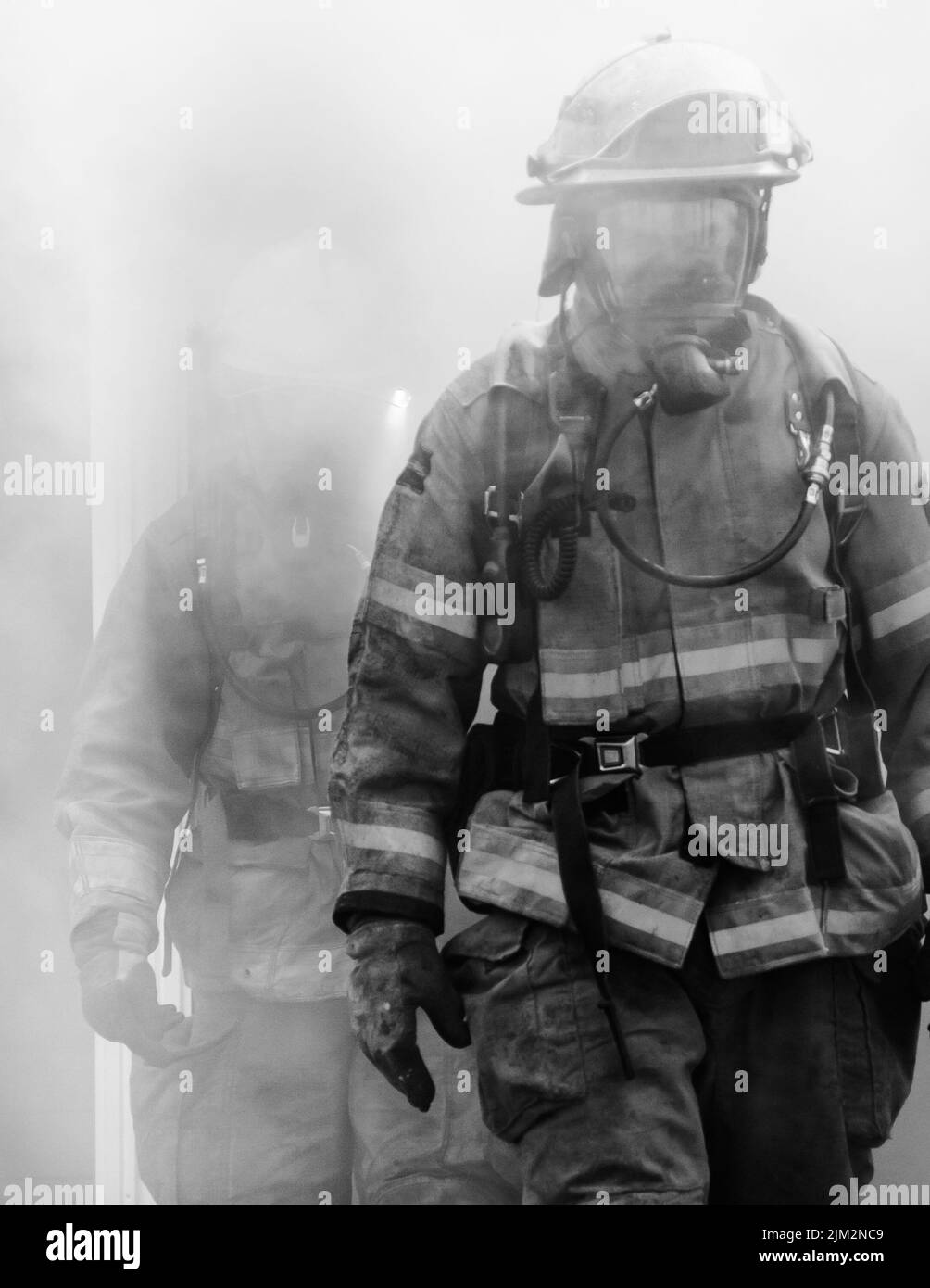Firefighter exiting a burning building Stock Photo