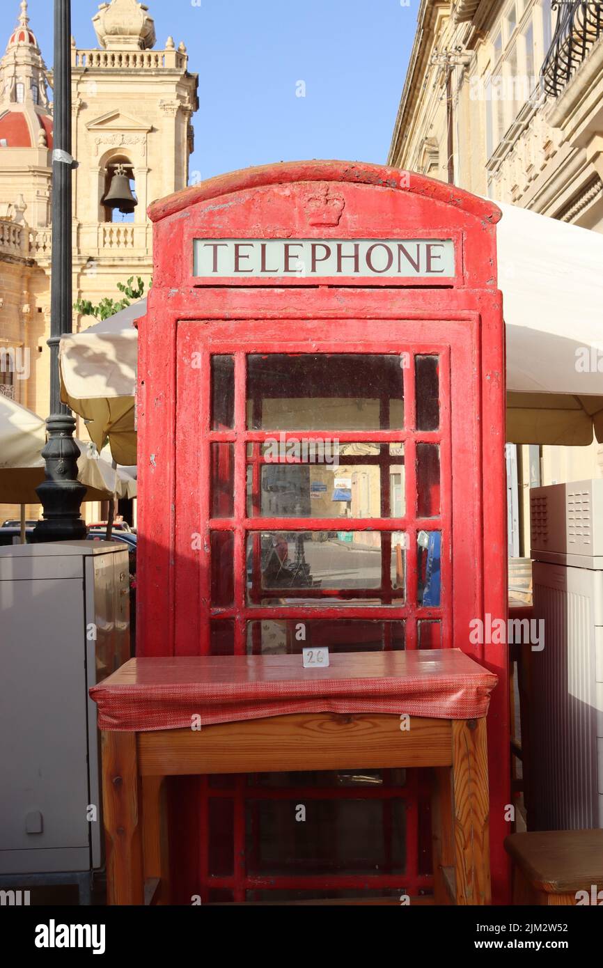 A red British phone box, situated between telecommunication cabinets creates an intimate dining area with a table for two. Just ring for service! Stock Photo