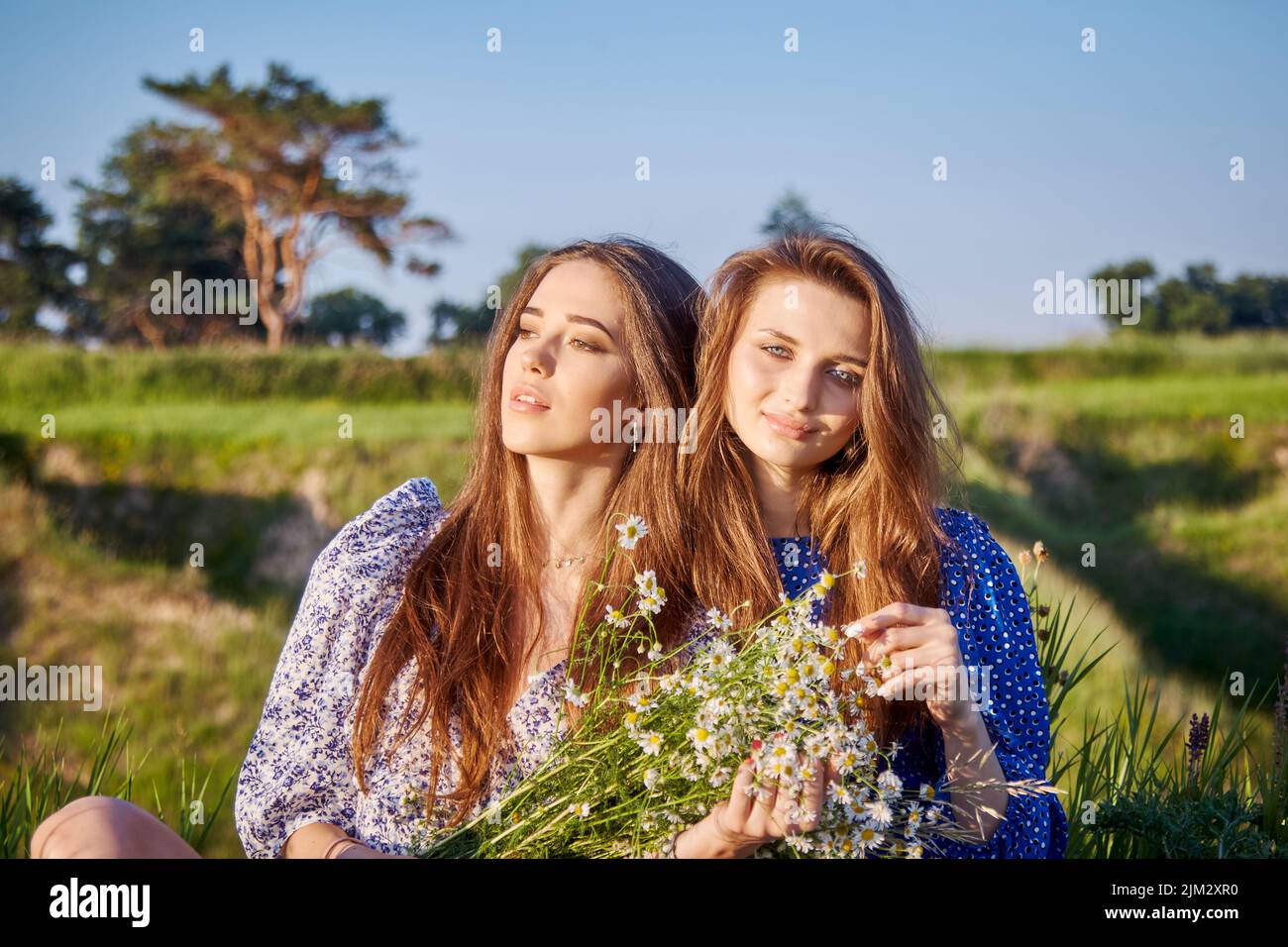 two young beautiful girls with a bouquet of flowers in nature Stock ...