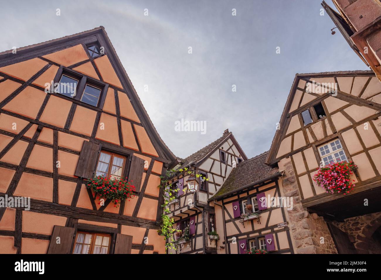 Old homes, stores and church with beautiful architecture in Alsace. Low angle.  Stock Photo