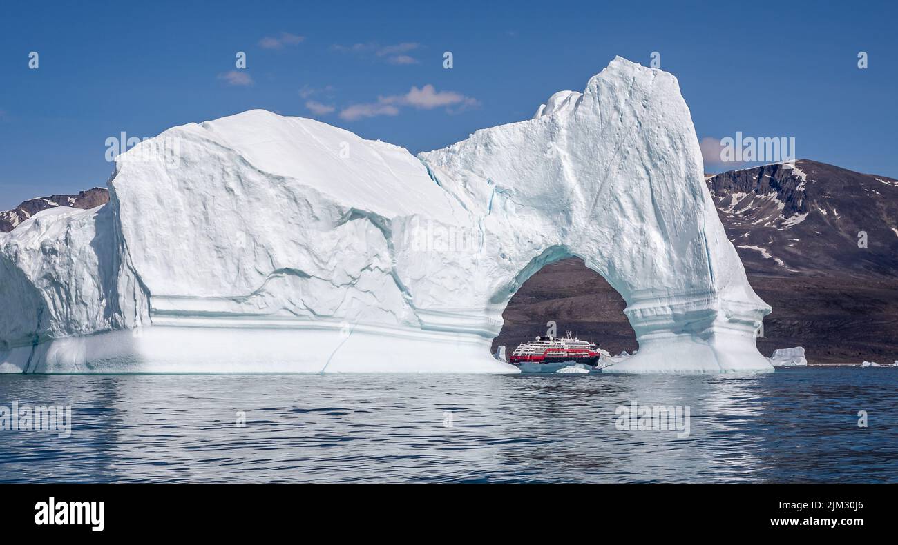 Hurtigruten's MS Fridtjof Nansen expedition  cruise ship seen through an arch in a gigantic iceberg at Disko Bay, Greenland on 18 July 2022 Stock Photo